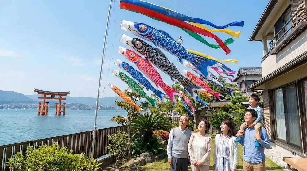 海沿いで立派な鯉のぼりを家族で見上げるイメージ画像